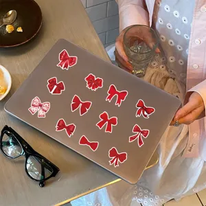 Detail view of red bow aesthetic decorative stickers applied on laptop for notebooks.