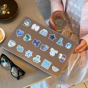 Detailopname van schattige blauwe esthetische graffiti-stickers op een laptopoppervlak.