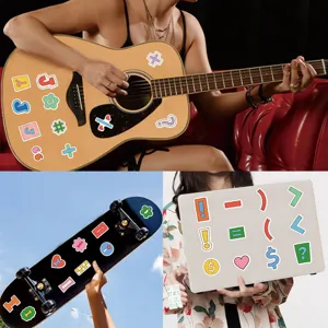 Detailed view of colorful cartoon English letter and symbol stickers applied on guitar and laptop.