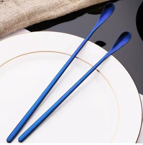 Close-up detail view of long-handled blue stainless steel mixing spoon on white plate