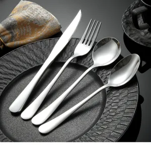 Stainless steel cutlery set detail shot, featuring fork, knife and spoons on dark plate.