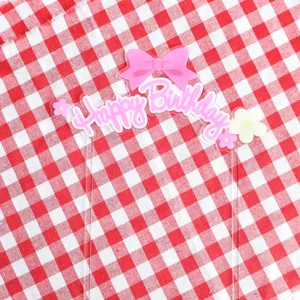 Acrylic Happy Birthday cake topper detail with cute pink bow and floral party decoration.