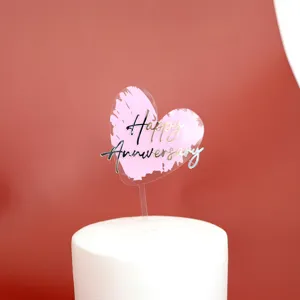 Close-up van hartvormige acryl taarttopper met Happy Anniversary tekst voor feestelijke decoratie.