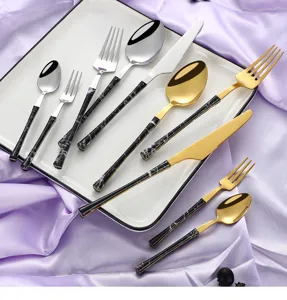 Detailed view of stylish stainless steel cutlery set with black marble handle and gold finish.