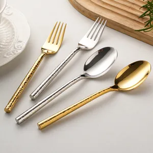 Stainless steel hammered tableware set including gold and silver spoons and forks.