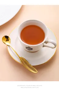 Élégant ensemble tasse et soucoupe à café en céramique avec bord doré et cuillère plume.