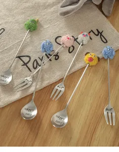 Detailed view of cute cartoon stainless steel spoons and forks with plush monster charms.