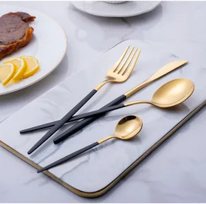 Detailed view of gold stainless steel flatware set with black handles, elegant table setting.