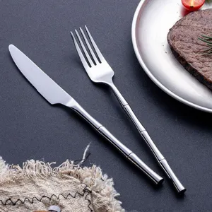 Ensemble de couverts en acier inoxydable avec poignée design bambou pour table moderne.