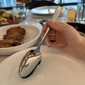 Foto de detalle de una cuchara de acero inoxidable pulido en una mesa de restaurante.