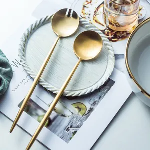 Gold stainless steel salad serving spoon and fork set, elegant cutlery for restaurant use.