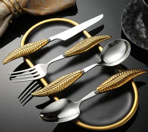 Detailed view of gold feather handle stainless steel cutlery set, elegant tableware design.