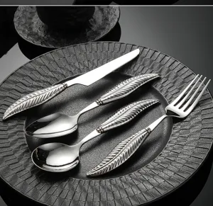 Closeup of elegant stainless steel cutlery with detailed feather handle design for dining.