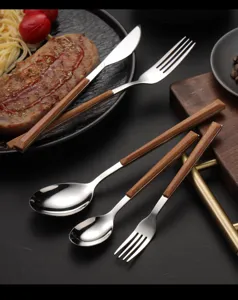 Stainless steel cutlery set with wood-grain handle, elegant steak knife and fork for dinner.