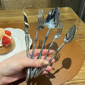 Close-up detail view of French stainless steel cutlery set displaying exquisite carved handles.