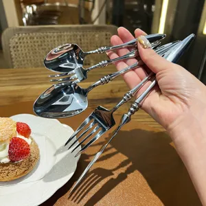 French vintage stainless steel fork and spoon set, ornate embossed handle detail, detail view.