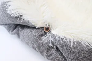 Close-up detail of soft pet bed with fluffy white plush interior and grey fabric exterior.