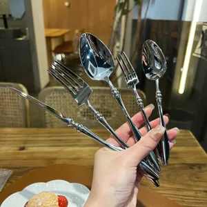 Close-up of polished stainless steel cutlery set held in hand, featuring vintage french style.