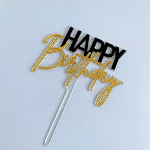 Détail de cake topper Happy Birthday en acrylique, lettrage noir et doré pour fête.