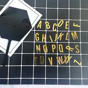 Gros plan détaillé de lettres de l'alphabet en acrylique doré et d'accessoires de gâteau.