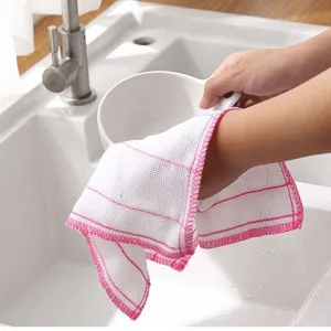 Gros plan d'un torchon de cuisine blanc en coton à bord rose nettoyant dans l'évier.