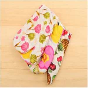Dettaglio guanto da forno in cotone trapuntato con stampa colorata di fiori e frutta.