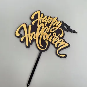 Vista detallada del adorno para tarta de Halloween de acrílico negro y dorado con texto.