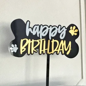 Dettaglio topper torta compleanno animale in acrilico, design osso con scritta e zampe.