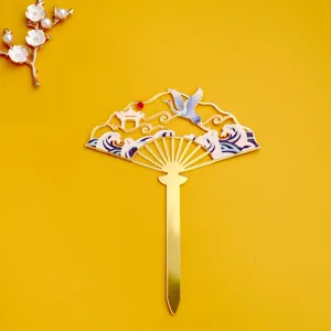 Detalle de decoración de pastel en abanico dorado estilo chino con grulla y olas elegantes.