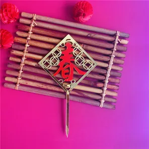 Detail view of golden acrylic Chinese New Year cake topper with red Chun character design.