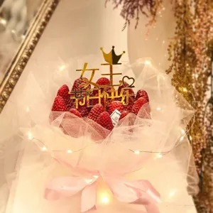 Detail shot of strawberry bouquet cake topper set with crown and fairy lights decoration.