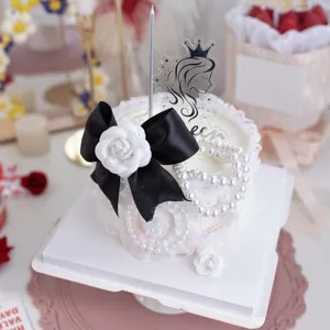 Détail de décoration de gâteau perle nœud camélia exquis, élégant ruban noir et fleur blanche.