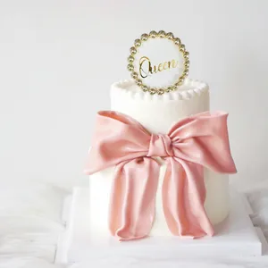 Detailed view of the elegant acrylic Queen cake topper and pink bow decoration for elegant parties.