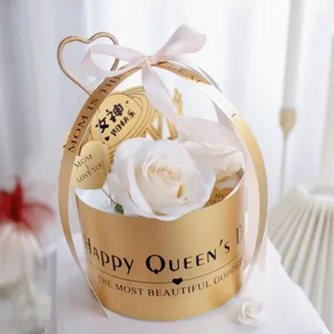 Boîte cadeau de fête des Mères avec camélia blanc, boîte ronde dorée et ruban élégant pour déco.