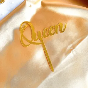 Gold acrylic Queen cake topper detail view, shiny surface cake decoration for party.