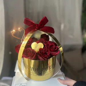 Boîte cadeau de roses rouges exquise avec poignée dorée et nœud en velours, vue détaillée.