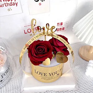 Décoration de boîte cadeau de roses artificielles rouges avec topper d'amour doré et texte.