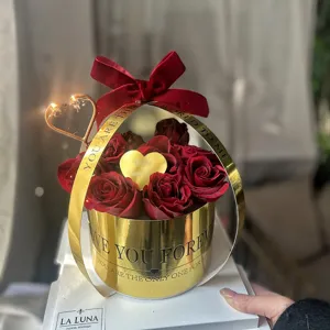 Coffret cadeau de roses rouges avec nœud en velours et cœur doré pour occasions.