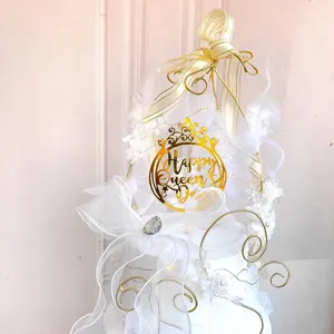 Elegant gold crown acrylic cake topper with white feathers and ribbons for Queen's Day.