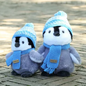 Detailed view of cute plush penguin toys wearing blue knit hats and cozy scarves outdoors.