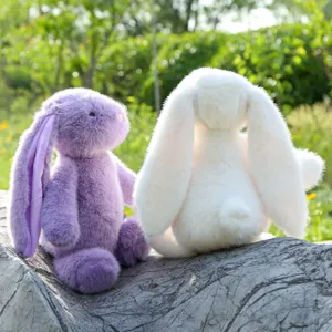 Detail shot of cute long-eared plush bunny toys sitting outdoors on a textured stone surface.