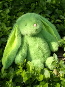 Green plush rabbit stuffed toy detail shot showing soft floppy ears and cute bunny design.