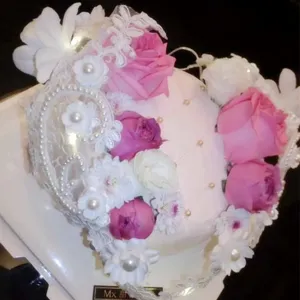 Detalle de pastel rosa con encaje blanco perlas y decoraciones de rosas para cumpleaños.