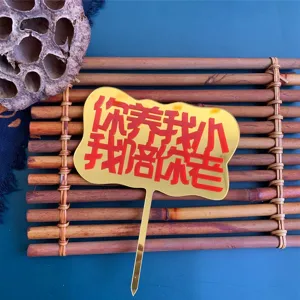 Close-up detail of the golden acrylic cake topper featuring engraved Chinese family blessing text.
