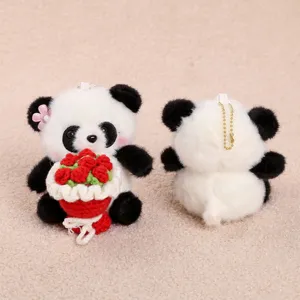 Detailed view of cute plush panda keychain holding red knitted flower bouquet close up.