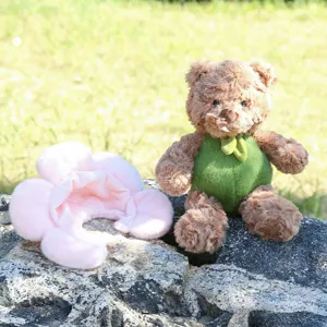 Niedlicher Plüsch-Teddybär mit grünem Outfit und rosa Blumen-Accessoire, weiche Stofftierpuppe.