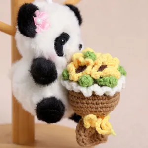 Close-up of cute crochet panda plush pendant holding a handmade knitted sunflower bouquet.