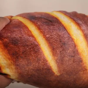 Primo piano dettaglio di cuscino peluche baguette realistico morbido pane giocattolo.