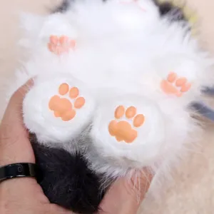 Close-up detail of cute cat paw plush bag pendant with soft white fur and pink silicone pads.