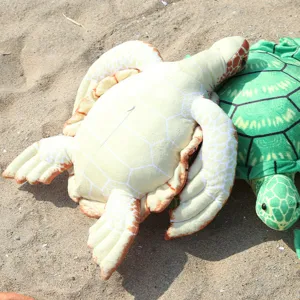 Detailed shot of realistic sea turtle plush toys resting on sandy beach background.